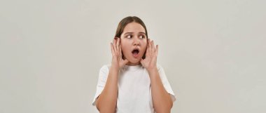 Şaşırmış Avrupalı genç kız, ağzı açık, başka tarafa bakıyor. Zoomer kuşağının kadın tişörtü. Modern gençlik yaşam tarzı kavramı. Beyaz arka planda izole edilmiş. Stüdyo çekimi. Boşluğu kopyala