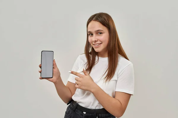 Adolescente Branca Sorridente Apontando Com Dedo Para Smartphone Olhando Para — Fotografia de Stock