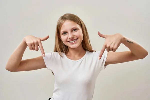 Menina Adolescente Branca Sorridente Apontando Com Dedos Para Baixo Olhando — Fotografia de Stock