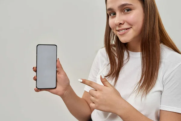 Καλλιεργημένη Εικόνα Του Χαμογελαστού Ευρωπαίος Έφηβος Δείχνει Smartphone Και Κοιτάζοντας — Φωτογραφία Αρχείου