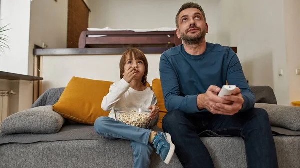 家庭でソファの上でテレビや映画を見て 焦点を当てた白人の父と息子 ポップコーンを食べる小さな子供 父親と子育て 家族関係と一緒に時間を過ごす レジャー — ストック写真