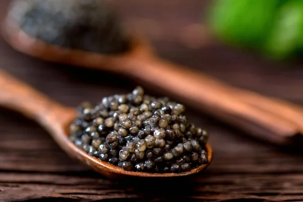 Wooden spoon with black sturgeon caviar, macro Royalty Free Stock Photos