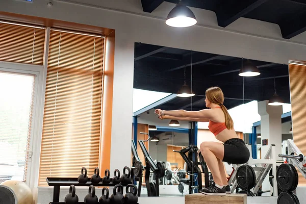 Вид збоку молода жінка робить статичні або ізометричні присідання в спортзалі — стокове фото