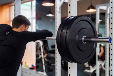 Modern spor salonunda halterli ve halterli genç adam.