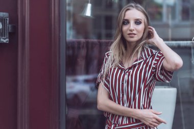 Uzun saçlı genç manken eski kafenin önünde poz veriyor.