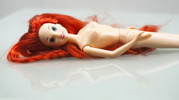 Barbie with red hair on glass table — Stock Photo, Image