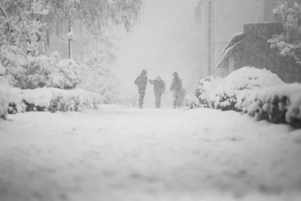 Paisagem urbana nevando com pessoas passando por — Fotografia de Stock