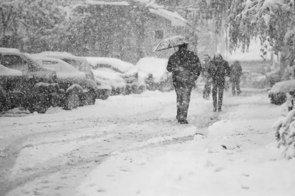 Verschneite Stadtlandschaft mit vorbeifahrenden Menschen Stockfoto