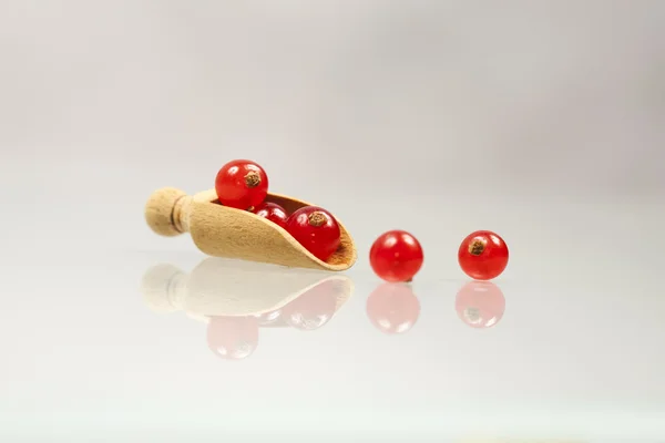 Grosellas rojas en una cuchara de madera — Foto de Stock