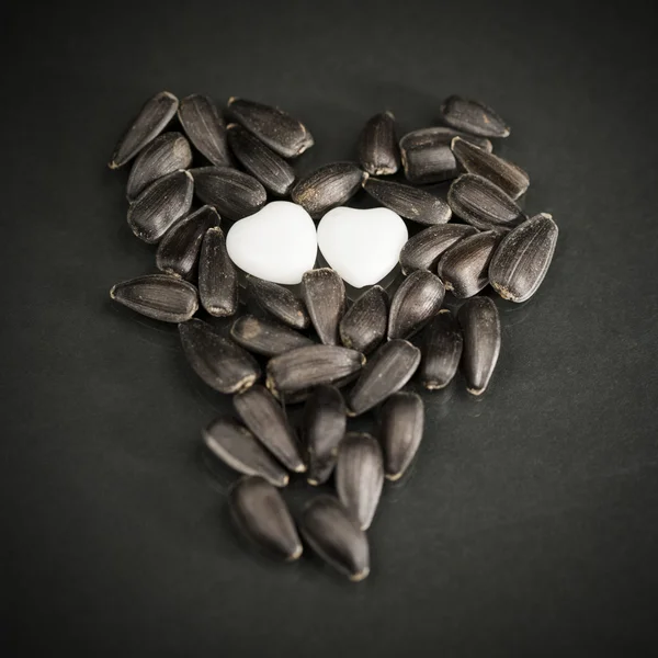 Sunflower seeds and white heart shaped agate — Stock Photo, Image