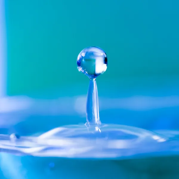 Round water drop falling into water — Stock Photo, Image