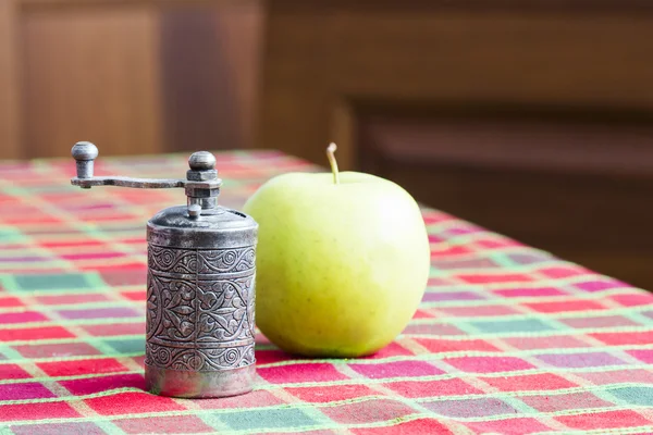 Still life composition with metallic pepper grinder and apple — Stock Photo, Image