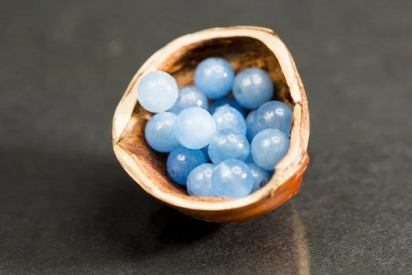Casca de avelã com pequenas pedras preciosas azuis e transparentes — Fotografia de Stock