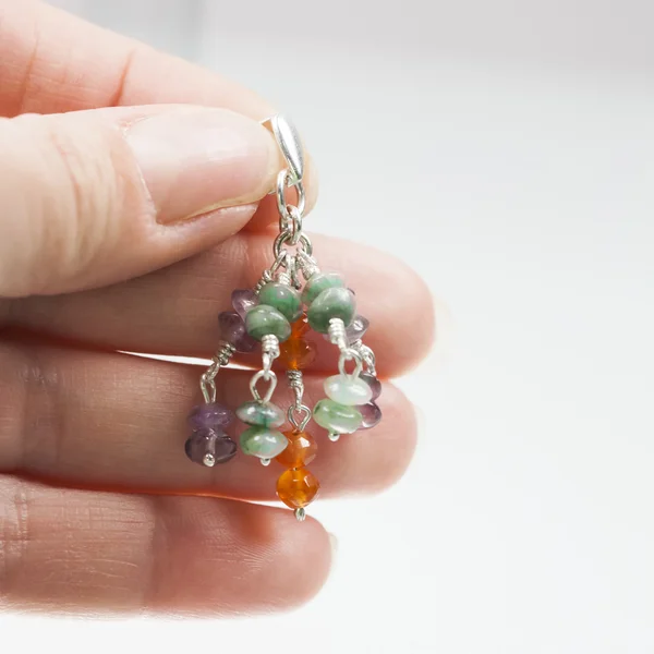 Hand holding Silver earrings with amethyst, agate and emerald gemstones — Stock Photo, Image