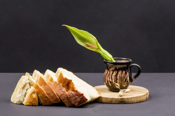 Tábua de corte, pão e vaso cerâmico com flor de Arum — Fotografia de Stock