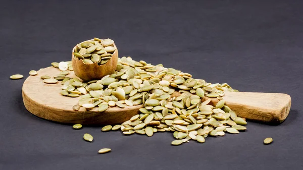 Kitchen cutting board and pumpkin unshelled seeds — Stock Photo, Image