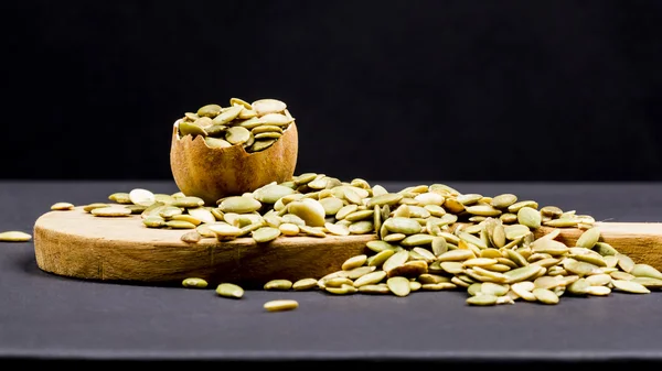 Kitchen cutting board and pumpkin unshelled seeds — Stock Photo, Image