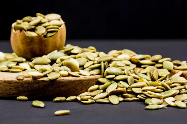 Kitchen cutting board and pumpkin unshelled seeds — Stock Photo, Image