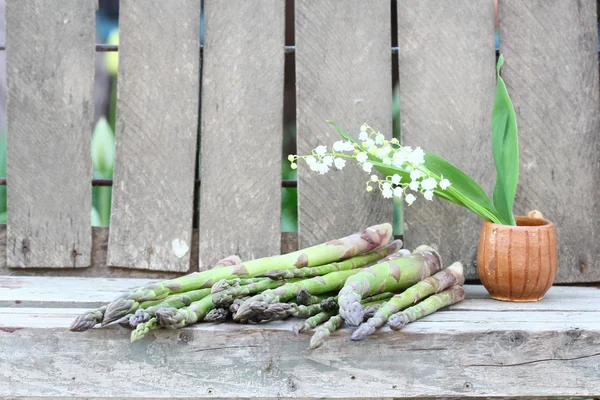 Asparagi e vaso di ceramica con fiori di giglio della valle — Foto Stock