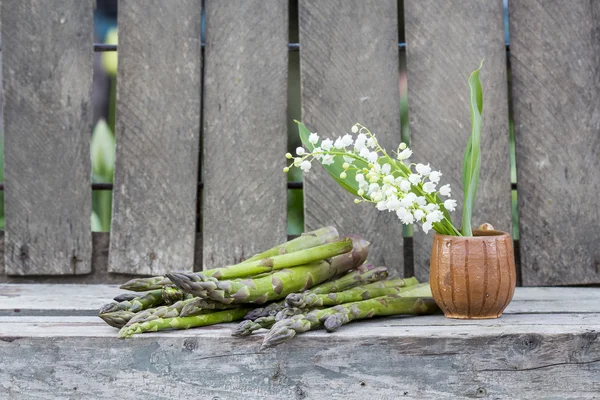 Asparagi e vaso di ceramica con fiori di giglio della valle — Foto Stock