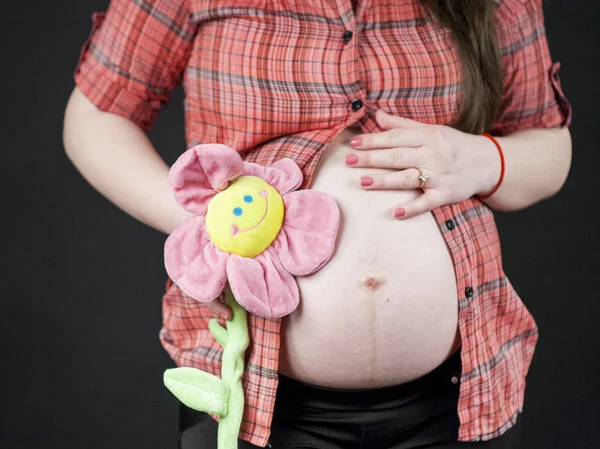 Mujer embarazada sosteniendo una flor de juguete — Foto de Stock