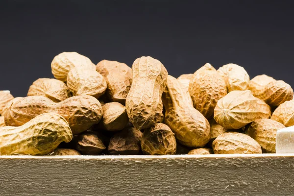 Erdnüsse in Schale in einer Holzkiste, mit schwarzem Hintergrund Stockfoto
