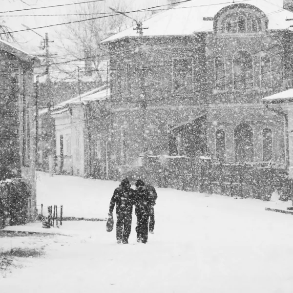 Manzara ile geçen insanlar kar yağışı — Stok fotoğraf