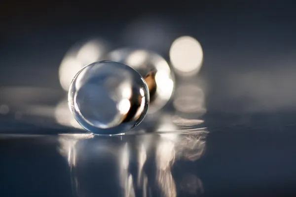 Abstrakt komposition med smukke, gennemsigtige, runde jelly kugler på en aluminiumsfolie med reflekser og mørk baggrund - Stock-foto