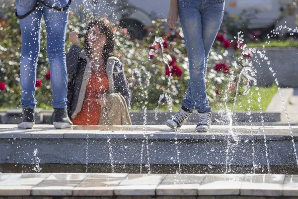 Капли воды из фонтана с молодыми девушками на ногах, одетые в джинсы — стоковое фото
