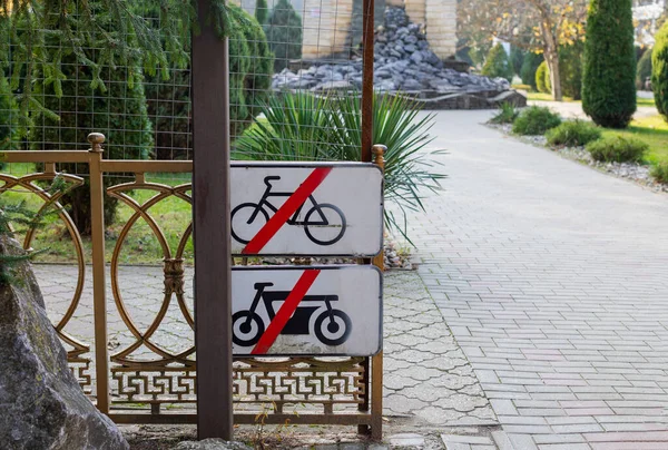 Carteles que prohíben el ciclismo y la scooter montados en una valla metálica en la entrada del parque de la ciudad. Peligro y precaución. No hay bicicleta. —  Fotos de Stock