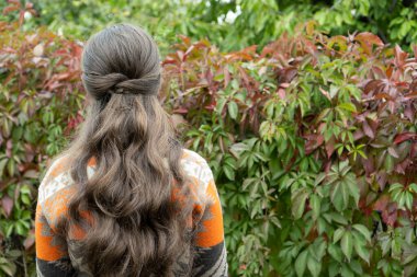 Sonbahar parkında hoş ve şık bir kadın. Sonbahar gelini saç stili. Uzun kıvırcık saçlı esmer kız ormanda dinleniyor. Özgürlük kavramı, boho tarzı kıyafetlerle. Hippi. Doğal kıvırcık ve parlak saçları var.
