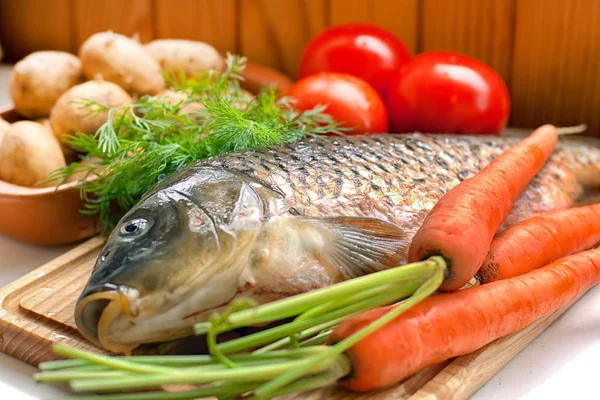 Pescado fresco en una tabla de madera con verduras — Foto de Stock