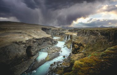 İzlanda 'nın turkuaz nehri ve günbatımı ile dağlık bölgelerdeki inanılmaz Sigoldugljufur kanyonunun manzarası. Arka planda volkanik manzara. Popüler turistik cazibe.