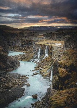 İzlanda 'nın turkuaz nehri ve günbatımı ile dağlık bölgelerdeki inanılmaz Sigoldugljufur kanyonunun manzarası. Arka planda volkanik manzara. Popüler turistik cazibe.