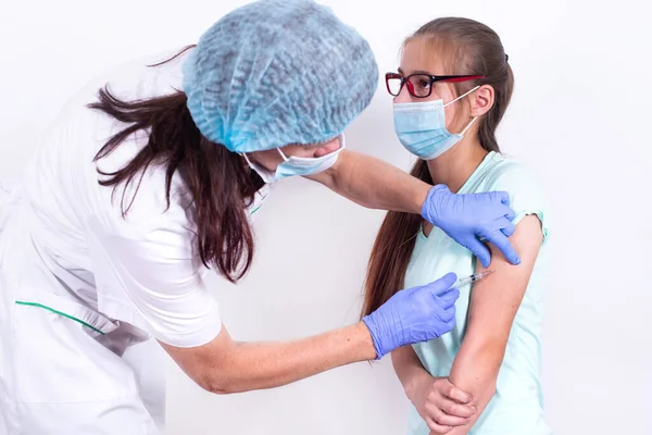 女性小児科医や看護師は、肩の患者にショットやワクチンを与える-若い女の子.インフルエンザ、パンデミックコロナウイルスに対するワクチン。ウイルスからの免疫のための人々の必須予防. — ストック写真