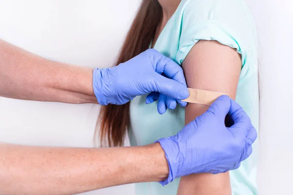 Artsen of verpleegkundigen lijmen verband op de schouder van patiënten na een injectie of vaccinatie. Een close-up. Vaccinatie tegen griep, pandemisch coronavirus. Verplichte preventie van virusimmuniteit. — Stockfoto