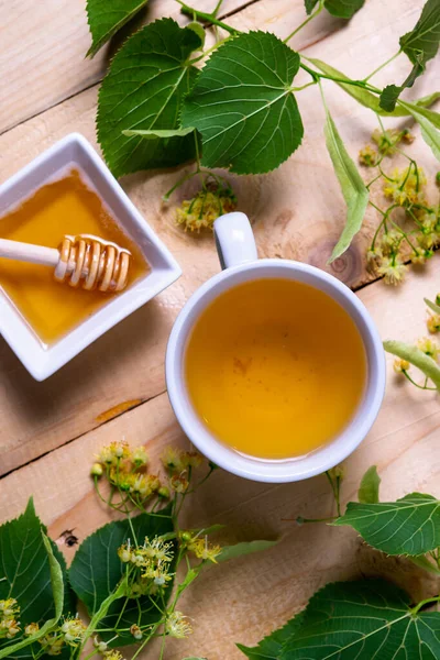 Una taza de té de tilo caliente con miel sobre un fondo de madera clara. Bebida antifría. — Foto de Stock