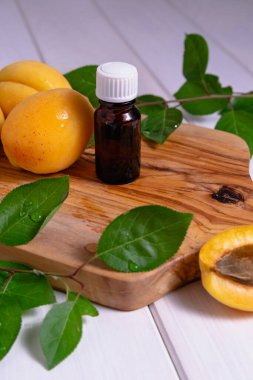 Kayısı yağlı, olgun taze meyve ve yapraklı koyu cam bir şişe. Doğal organik kozmetik