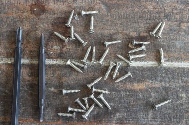 Tahta arka planda tornavida ve vidalar.