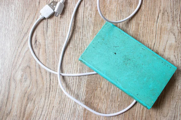 Old and dirty power bank with mobile charger on the wooden table.