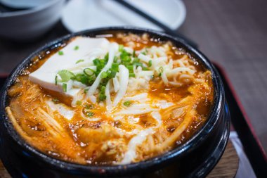 Kimchi Jjigae ya da Kimchi çorbasını siyah bir çömleğin içine koy. Geleneksel Kore yemekleri..