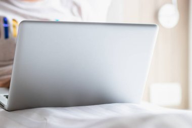 Work from home during the outbreak of the virus. Woman working with a laptop on a bed.