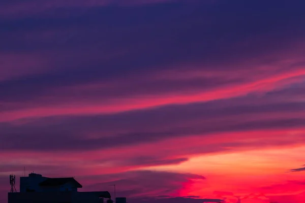 Pink and blue clouds and sky with a silhouette of a house. Twilight sky.