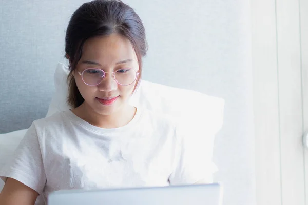 Work from home during the outbreak of the virus. Asian young woman working with a laptop on a bed.