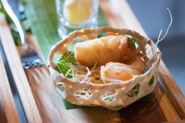 Dekoratif yiyeceklerle örülmüş bir sepetin içinde kızarmış böreklerin yakın çekimi. Seçici odak.