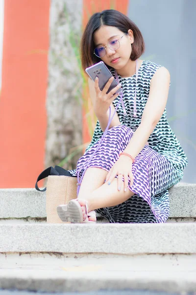 美丽的亚洲女人坐在花园里玩手机 和大自然一起度假 — 图库照片