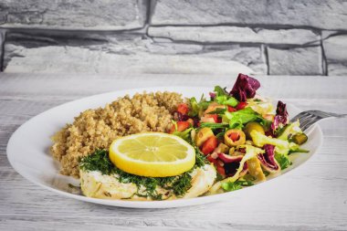 Taze, lezzetli vejetaryen yemeği. Mutfakta beyaz tabakta marullu ve kinoalı balık..