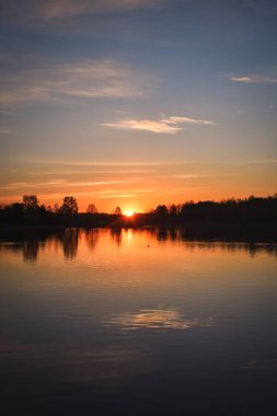 Polonya 'da harika bir sabah manzarası. Güneş renkli bir gökyüzünde, gölün üzerinde..