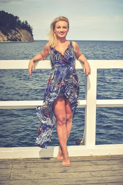 Klasik tarzda kadınsı bir tatil. Gdynia 'daki Polonya Denizi kıyısındaki ahşap iskelede güzel bir kadın..