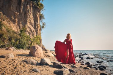 Yaratıcı tatil deniz kenarı seansı. Sahilde zarif kırmızı elbisesiyle güzel bir kadın..